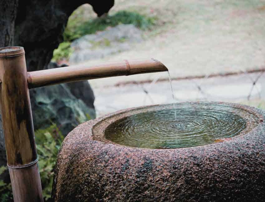 Une fontaine japonaise en pierre (fontaine Tsukubai) alimenté par un bambou