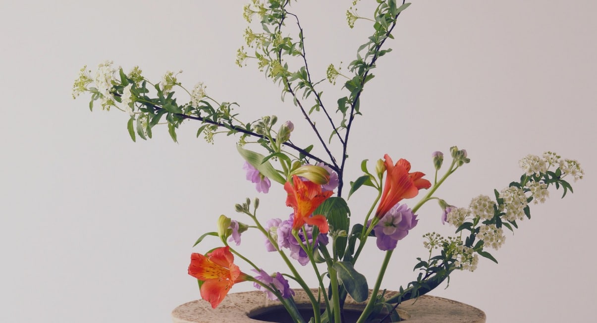 Composition florale japonaise ikebana epuree avec fleurs et branches dans un vase